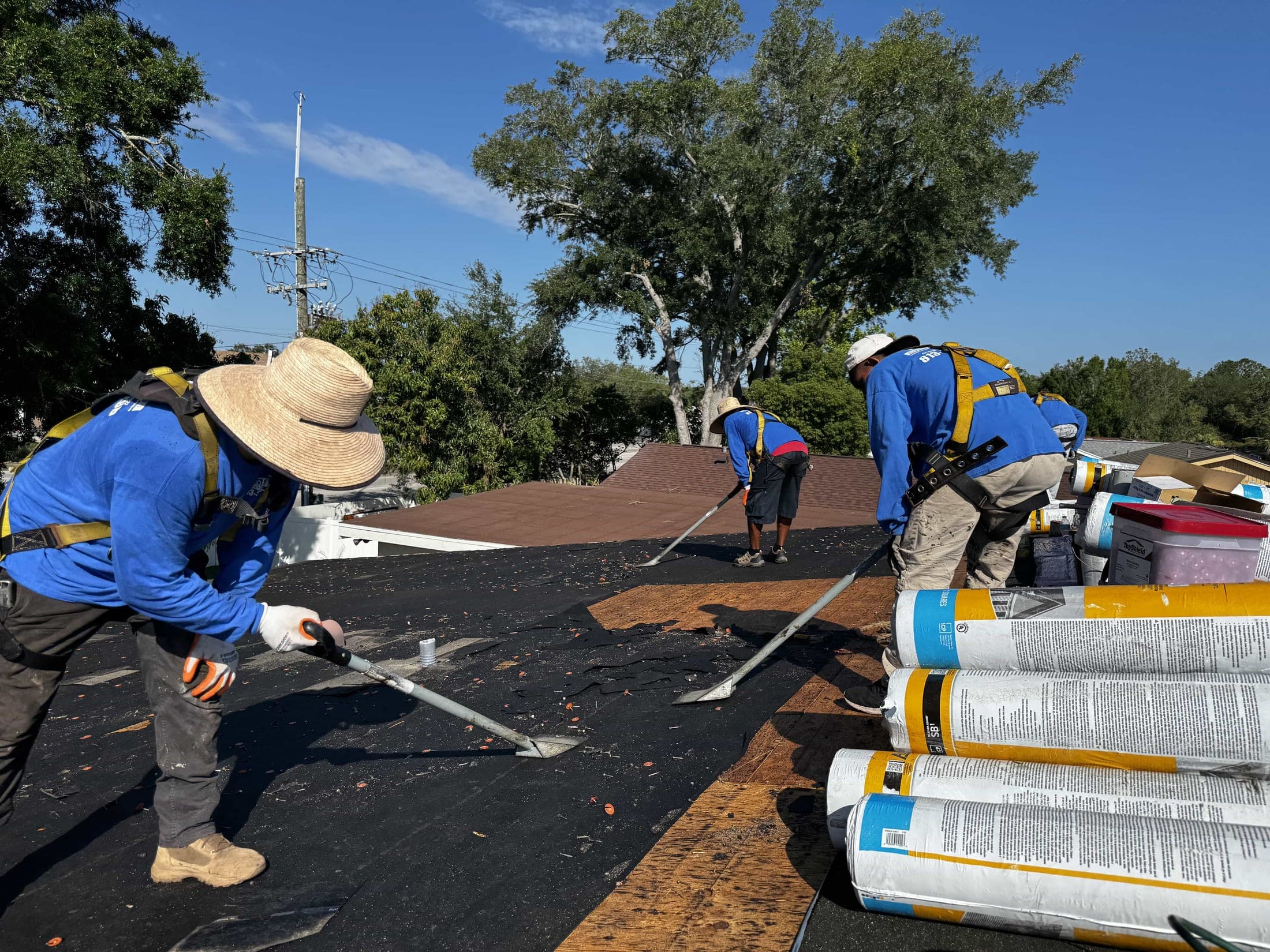 Colossus Construction crew removing old shingles during a tear-off