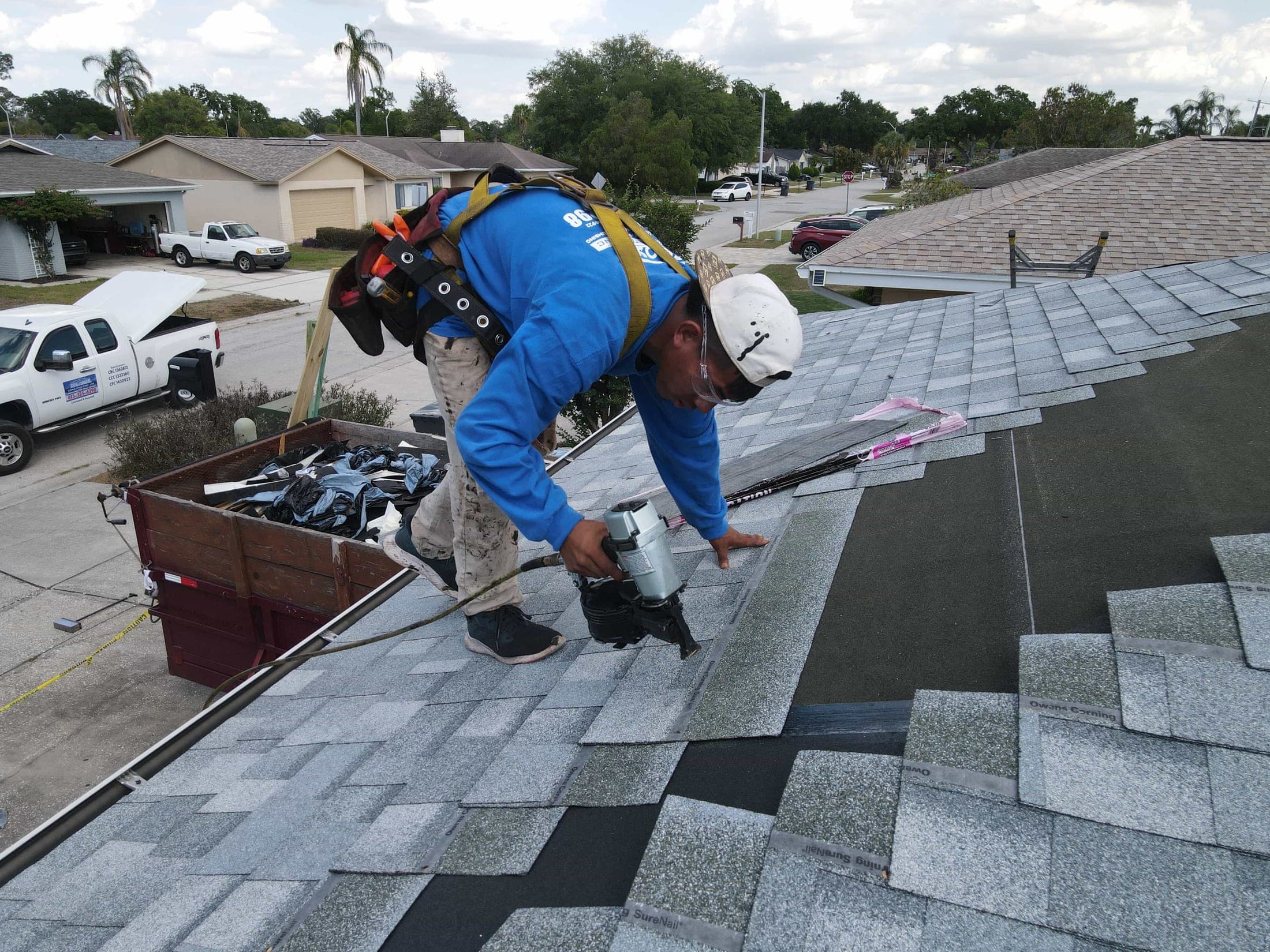 Roofer nailing down new shingles on a Tampa Bay home