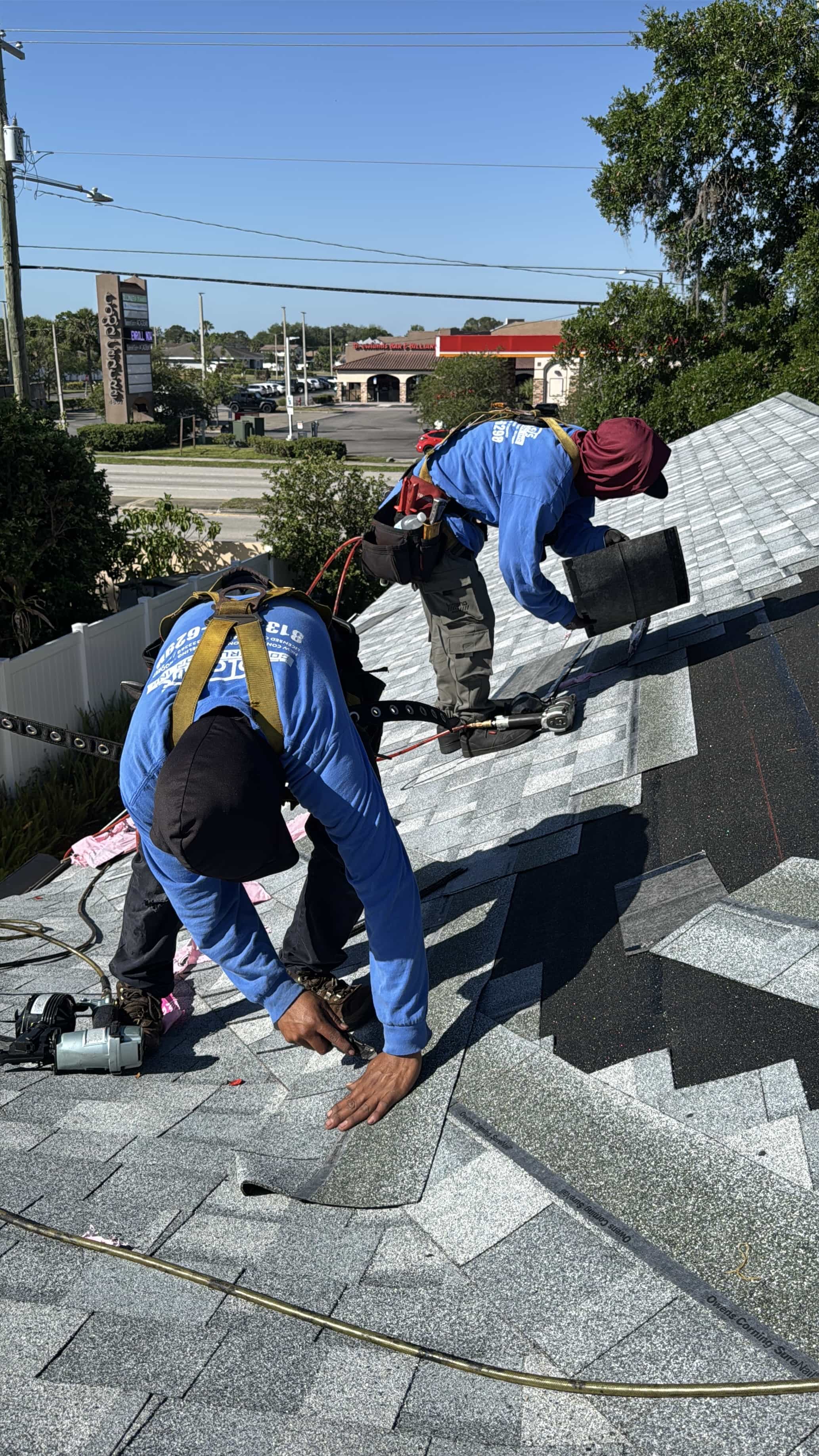 Two roofers installing new architectural shingles
